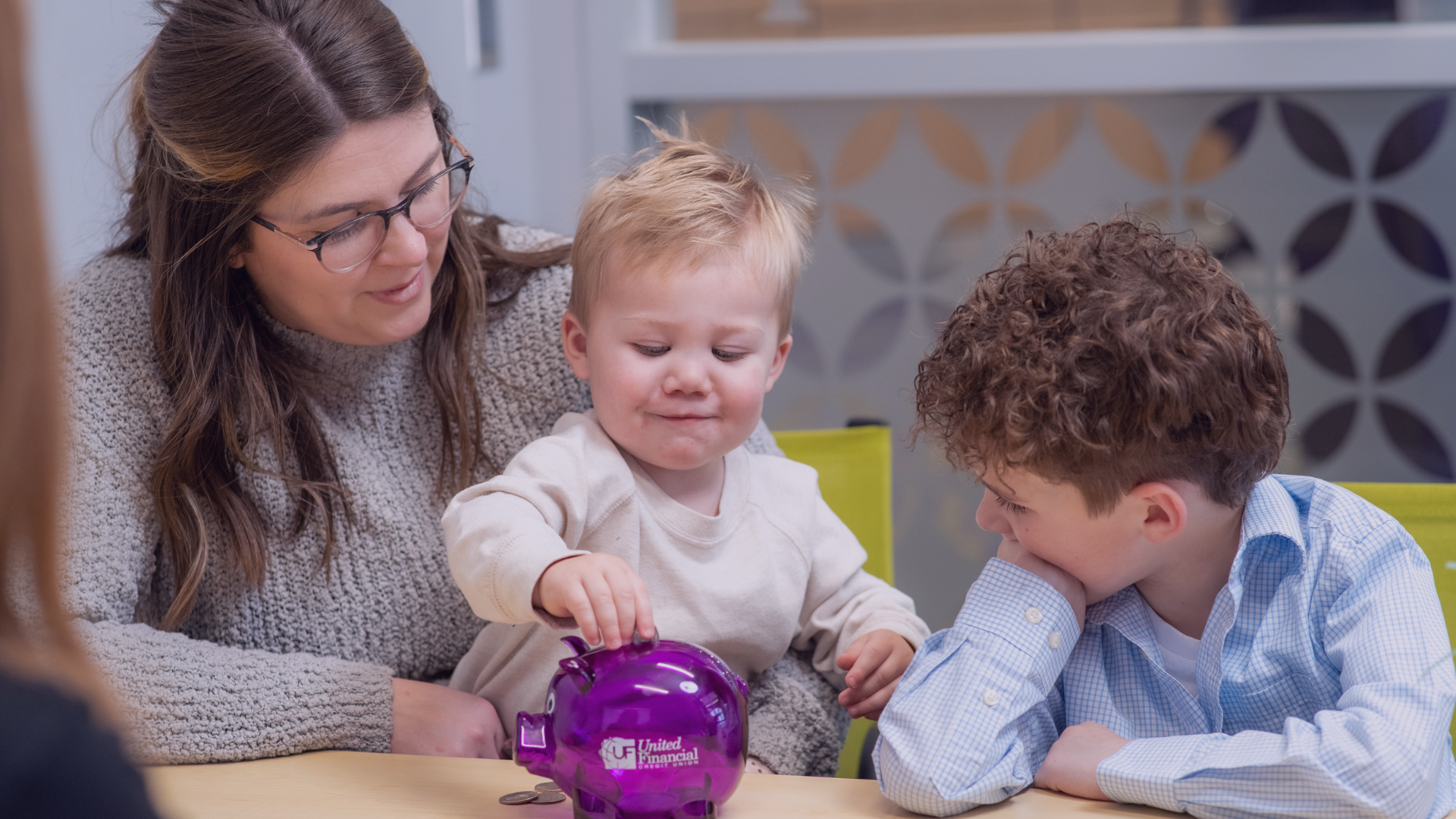 children putting money in a piggy bank with mom