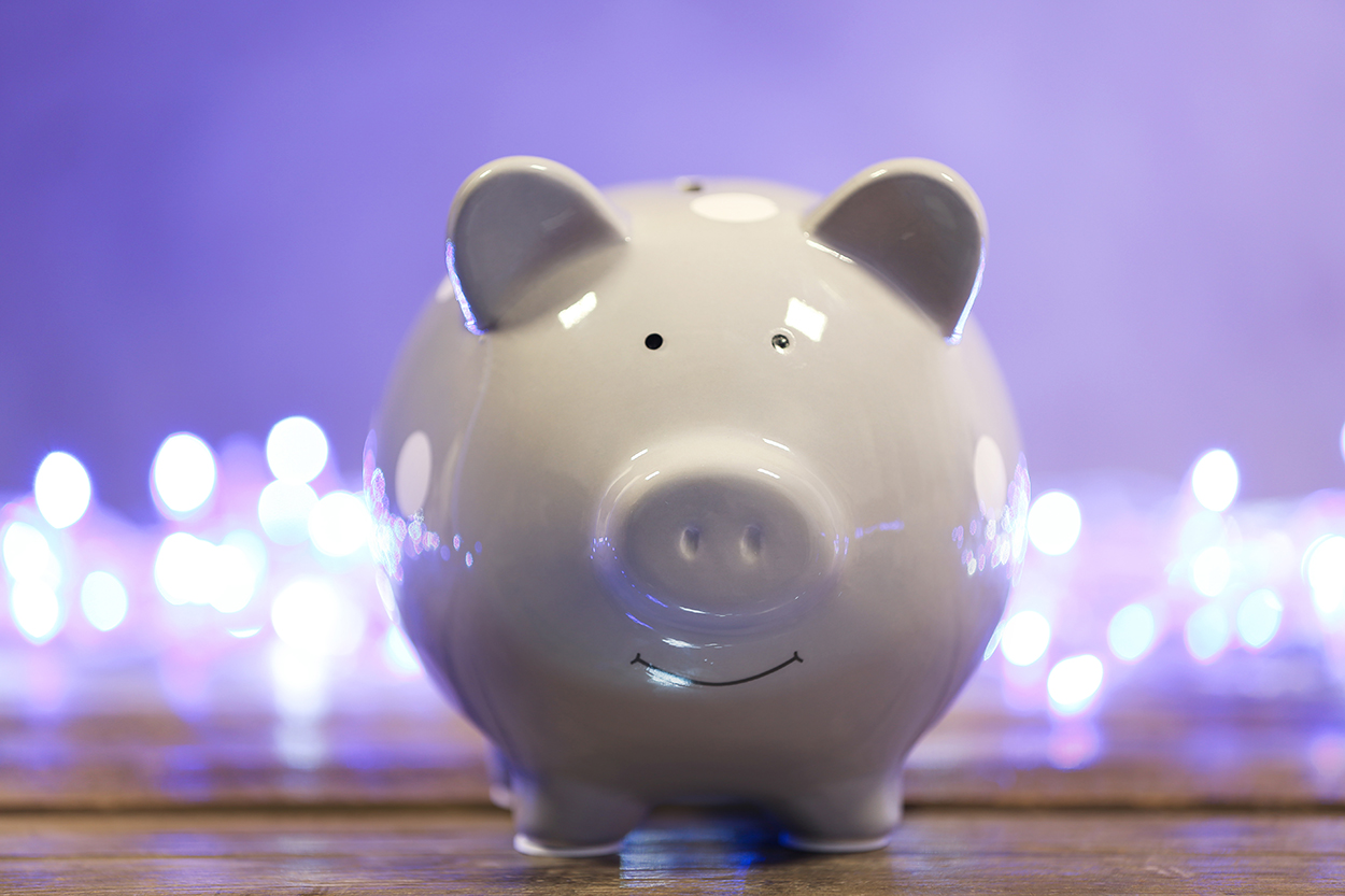 Cute piggy bank on table against blurred Christmas lights